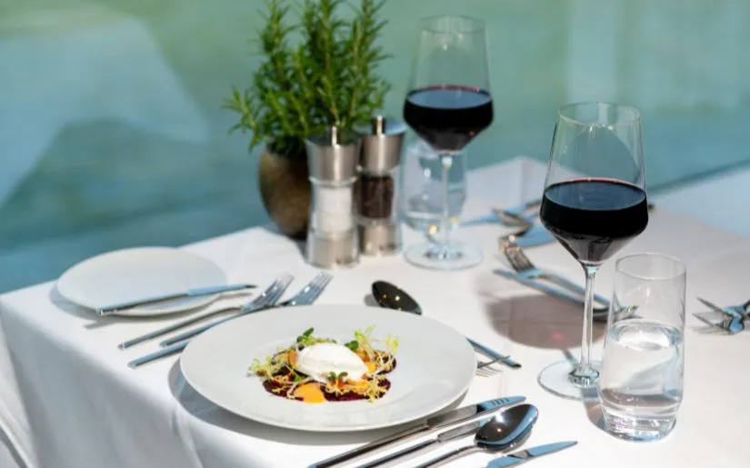 Gold-Essen Abendessen als Menügang auf der Thurgau Gold: gefüllter Teller und Gläser mit Rotwein sowie Besteck, Pfeffer und Salz.